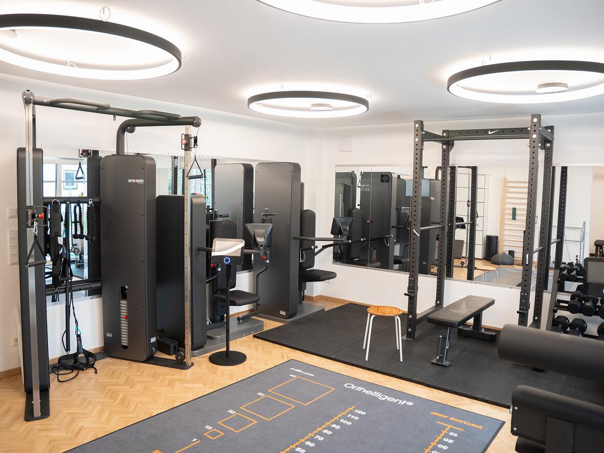Fitnessraum mit Trainingsgeräten, Hanteln und Übungsteppich