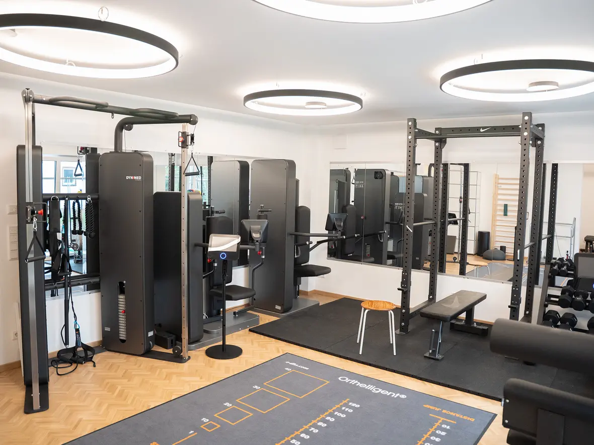 Fitnessraum mit Trainingsgeräten, Hanteln und Übungsteppich