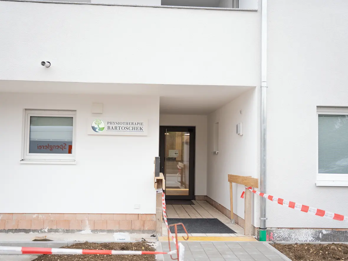 Eingang zur Physiotherapie Bartoschek mit Rampe und Bauabsperrung.